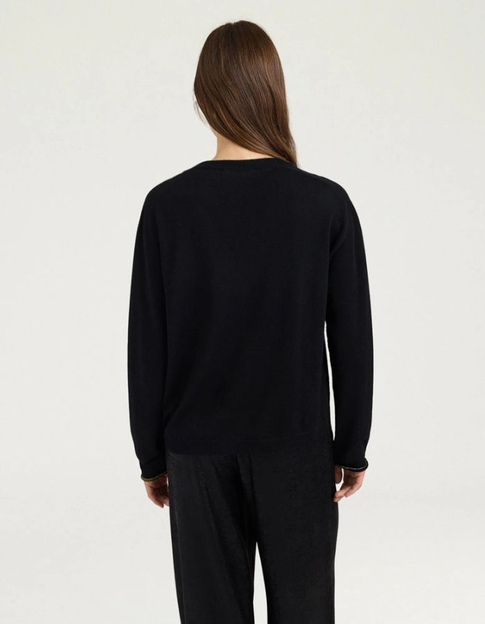 Dos du Pull pour femme en pure laine noire, modèle Astrid de la marque MOMONI. Présente une maille teinté en pièce et de délicates bordures en lurex doré aux finitions.