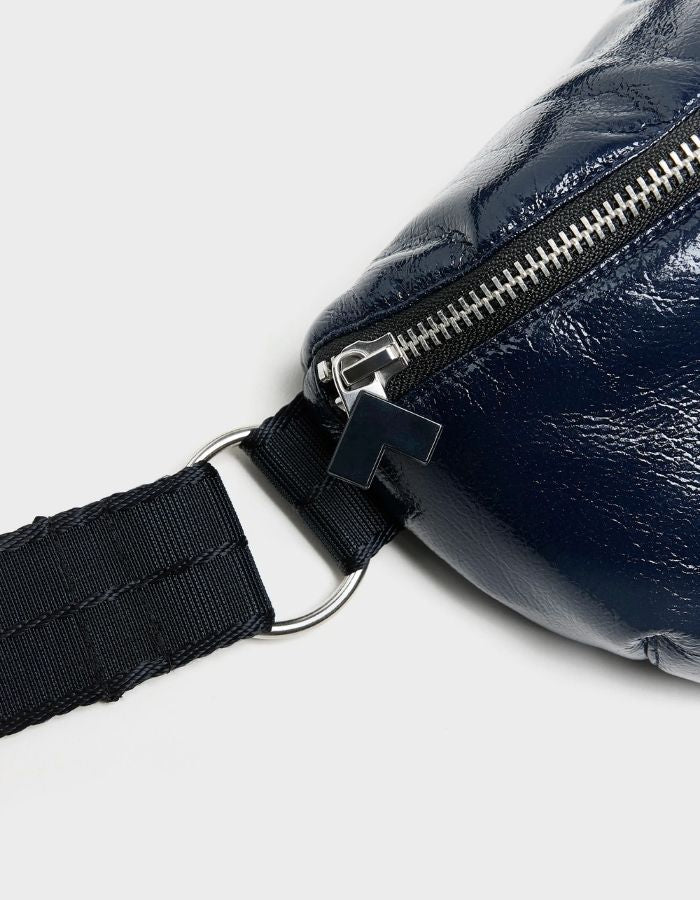 Zip du Sac banane bandoulière pour femme en simili-cuir brillant bleu marine matelassé motif vagues avec bandoulière ajustable en coton, modèle Hosie Sling Bag de la marque Bellerose.