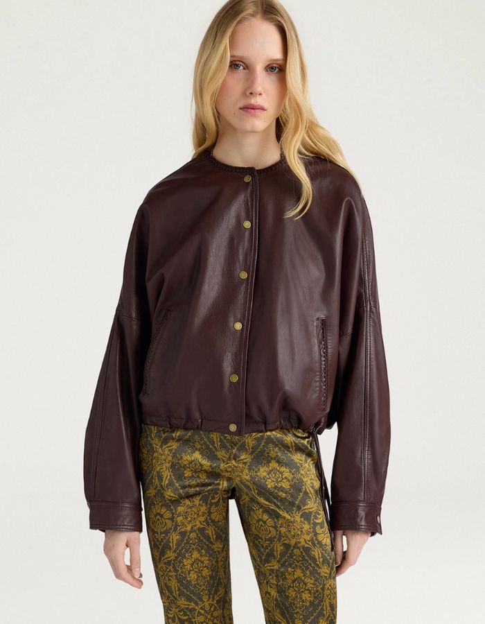 Vue de face de la Veste bomber courte pour femme en cuir d'agneau marron, modèle Kaldor de la marque MOMONI. Présente une coupe carrée avec cordon de serrage au bas et des boutons-pression en laiton vieilli.