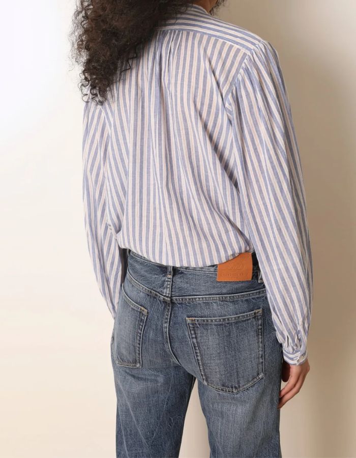 Dos de la Blouse ample pour femme en coton bleu à rayures, modèle Fa de la marque Laurence Bras. Présente un col rond, des volants asymétriques sur le devant et des manches bouffantes.