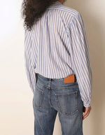 Dos de la Blouse ample pour femme en coton bleu à rayures, modèle Fa de la marque Laurence Bras. Présente un col rond, des volants asymétriques sur le devant et des manches bouffantes.