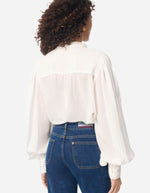 Blouse blanche Gania en voile de coton avec col officier, manches bouffantes et empiècements plissés.