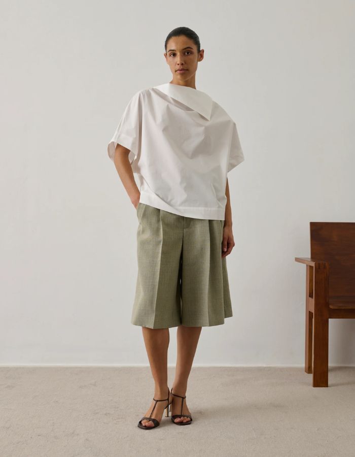 Mannequin portant une blouse Issa blanc cassé en coton biologique avec col tombant et ouverture boutonnée à l'épaule.