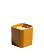 Bougie Facettes Bois de Santal 650Gr en grès fauve, carrée, avec quatre mèches allumées.