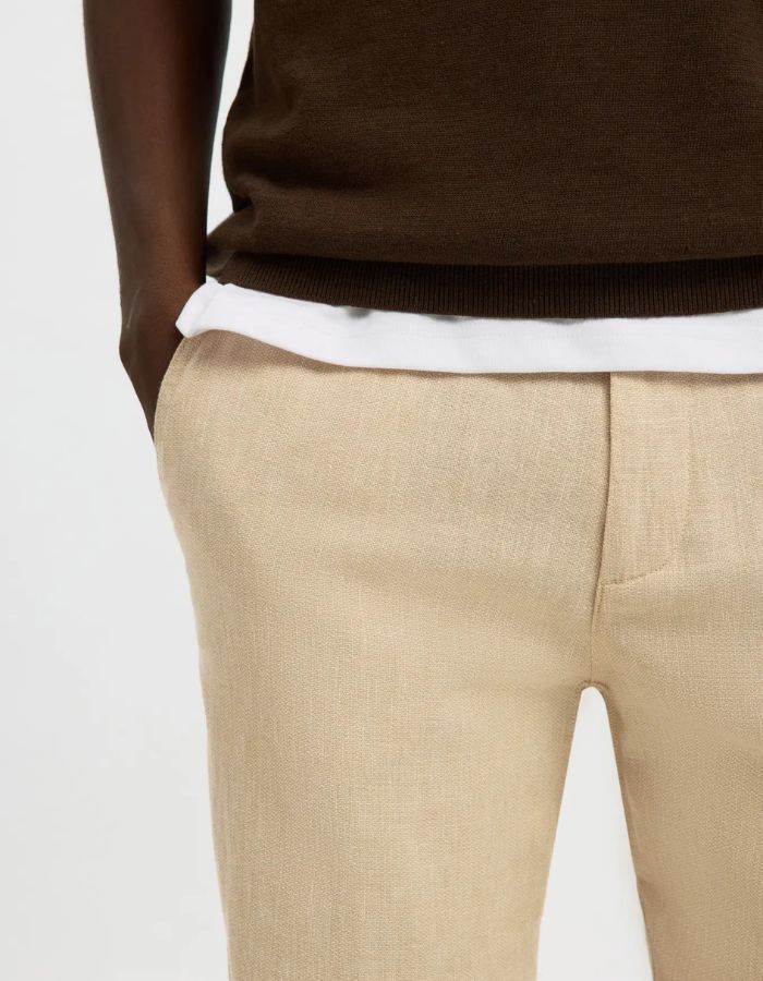 Pantalon Brody Slim Tapered beige en lin et coton, porté par un homme.