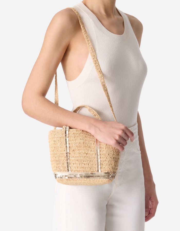 Cabas XS en raphia tressé main avec sequins dorés, porté épaule par une femme.