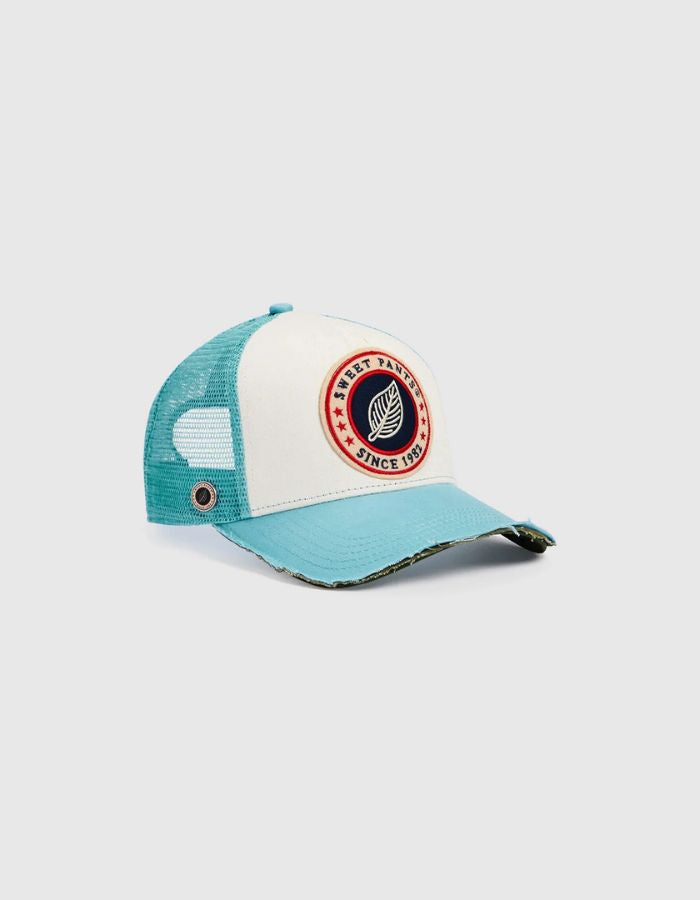 Vue de côté de la Casquette Trucker bicolore Home Run de Sweet Pants, coloris bleu Sea et blanc. Patch logo de la marque à l'avant, visière bleu océan avec effet usé sur la tranche et filet d'aération blanc à l'arrière