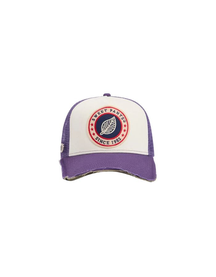 Casquette Trucker bicolore Home Run par Sweet Pants, coloris violet Imperial et blanc. Patch logo de la marque cousu à l'avant, visière violette avec bordure effet usé et panneau arrière en maille filet blanc.