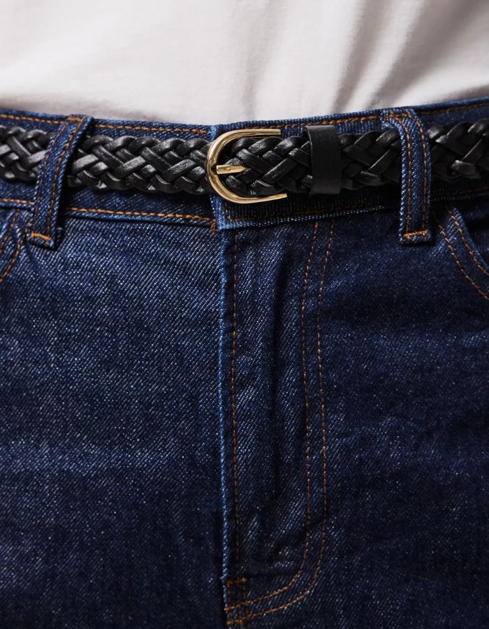Gros plan sur la Ceinture fine pour femme modèle Avery de la marque Pieces, en cuir véritable tressé de couleur noire avec une boucle métallique arrondie classique.