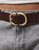 Boucle de la Ceinture pour femme en cuir suédé véritable de couleur marron chocolat Hot Fudge, modèle Juva de la marque Pieces. Présente une bande de 3 cm de large en daim mat et doux, fermée par une boucle rectangulaire en métal doré brossé mat.