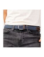 Ceinture tressée élastique bleu marine avec motif chevron, finitions cuir marron et boucle argentée, portée sur un jean.
