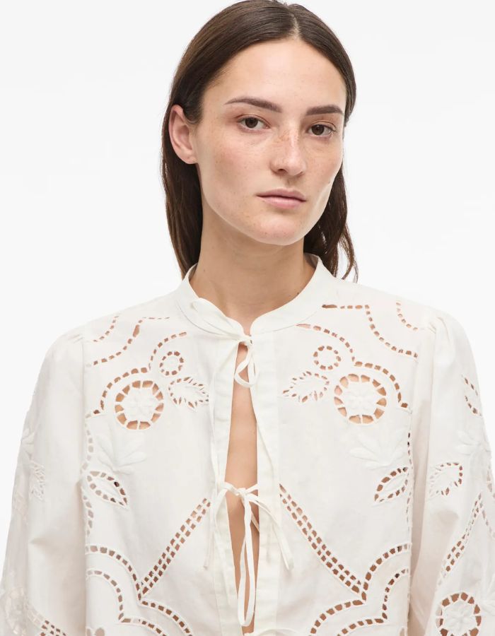 Chemise blanche Carin en popeline de coton bio avec col mao, broderie ajourée et fermeture à liens.