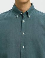 Vue de face de la Chemise pour homme Clay de la marque SELECTED en mélange lin et coton, coloris vert Balsam. Coupe Regular Fit, manches longues et col boutonné classique. Matière texturée intégrant du coton recyclé