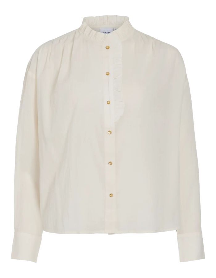 Chemise unie pour femme modèle Esma Frill de la marque Vila. Coupe droite à manches longues en coton bio de couleur blanc cassé écru Birch, ornée de volants plissés délicats le long du col et de la boutonnière.