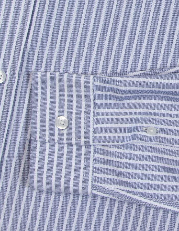 Poignet de la Chemise ajustée pour homme en coton Oxford à fines rayures bleu marine et blanches, modèle Malesherbes de la marque Maison Labiche. Présente un col boutonné, des boutons gravés et la mention 'Grand Cru' brodée en lettres fines sur la poitrine.