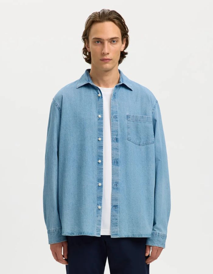 Chemise en denim bleu clair Carlo avec col classique, manches longues et poche poitrine, portée sur un t-shirt blanc.