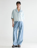 Femme portant une chemise en denim Poppa Ice Bleach Bellerose, coupe oversized et courte, avec un jean ample.