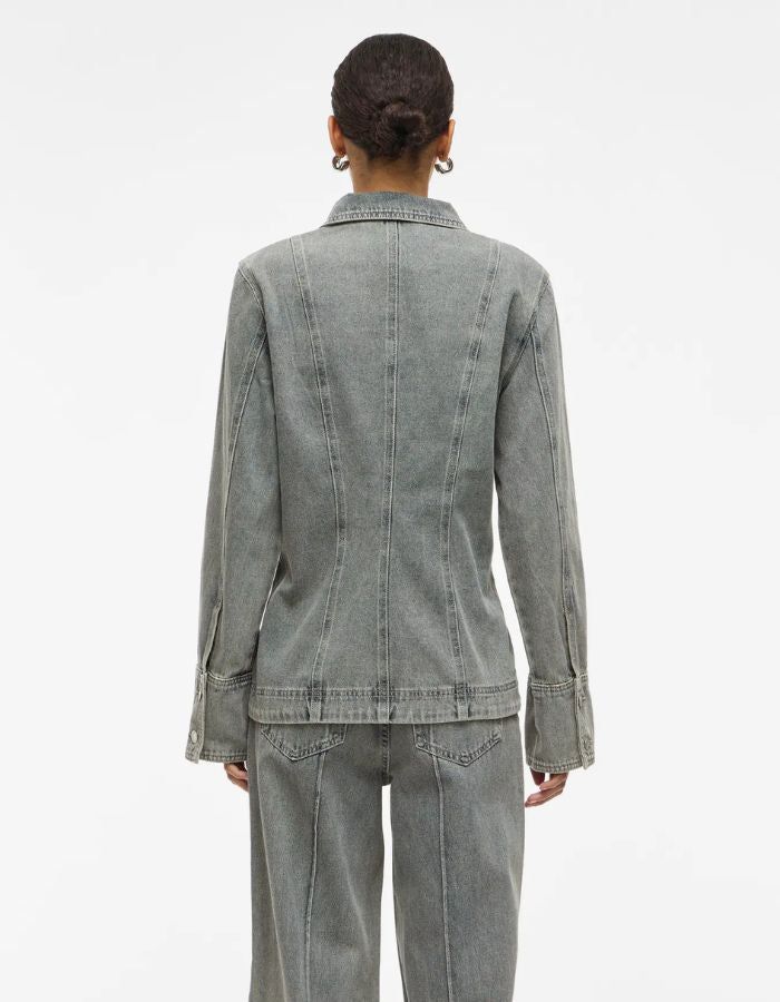 Dos d'une femme portant une chemise en denim gris clair à manches longues et coupe regular.
