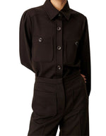 Chemise courte pour femme en tricotine fluide couleur ébène avec poches plaquées boutonnées et plis aux épaules, modèle Chemise Theodore couleur Ébène de la marque Sessùn.