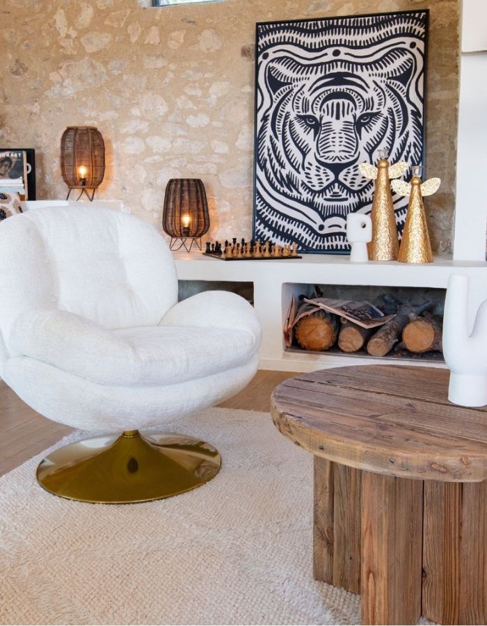 Fauteuil loveuse bouclette blanc pivotant avec base dorée dans un salon rustique chic.