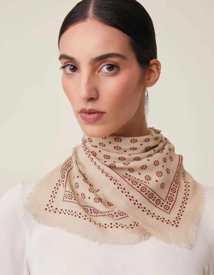 Foulard carré porté par une femme en laine style bandana graphique avec petites fleurs blanches et bords frangés, modèle Olaf N°676 Western de la marque MOISMONT.