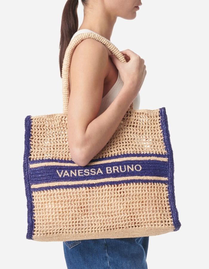 Grand panier en raphia tressé beige avec motif ajouré, bandes et logo Vanessa Bruno brodé bleu marine.