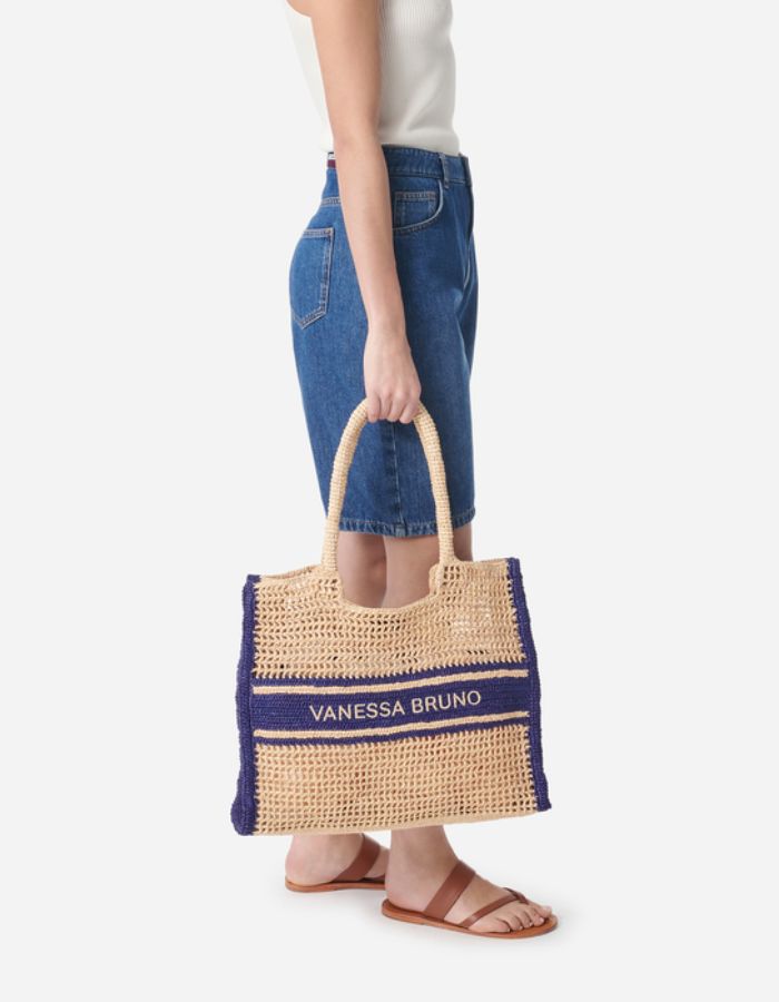 Grand panier en raphia tressé beige avec motif ajouré, bandes bleu marine et logo Vanessa Bruno brodé.