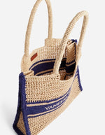 Grand panier en raphia tressé beige avec motif ajouré, bandes contrastées bleu marine et logo Vanessa Bruno brodé.