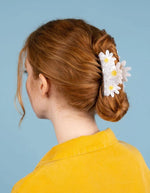 Grande pince à cheveux blanche nacrée avec trois pâquerettes et pistils jaunes, dans un chignon roux.