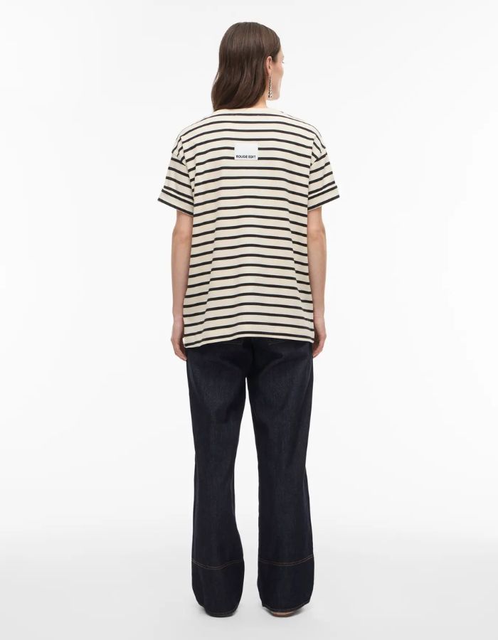 Femme de dos portant un jean Brixton coupe droite en denim bleu foncé et un t-shirt rayé.
