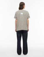 Femme de dos portant un jean Brixton coupe droite en denim bleu foncé et un t-shirt rayé.