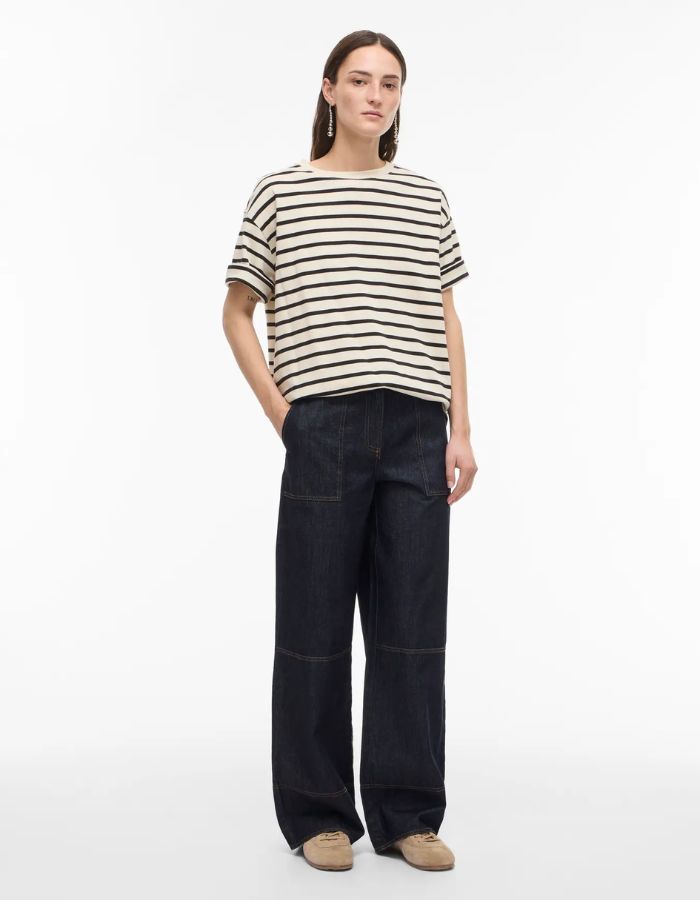 Jean Brixton coupe droite en denim bleu foncé avec surpiqûres, porté par une femme.