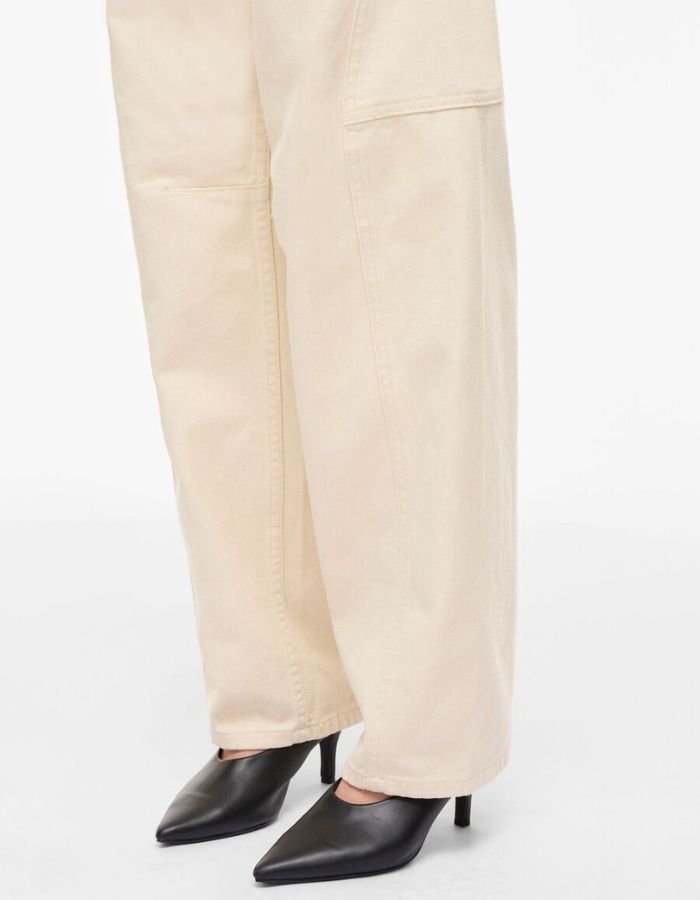 Détail de la jambe du Jean femme coupe tonneau de la marque VILA, coloris Birch (blanc cassé). Taille mi-haute, modèle cinq poches en coton mélangé recyclé avec une silhouette structurée.