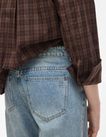 Bassin du Jean pour femme de couleur bleu clair délavé Light Blue Denim, modèle Tiana de la marque Rouge Edit. Présente une coupe droite ample contemporaine, une taille mi-haute avec des passants de ceinture et des finitions de boutons en métal doré mat Dull Gold.