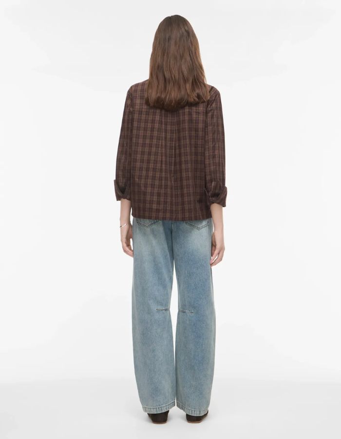 Silhouette de dos avec le Jean pour femme de couleur bleu clair délavé Light Blue Denim, modèle Tiana de la marque Rouge Edit. Présente une coupe droite ample contemporaine, une taille mi-haute avec des passants de ceinture et des finitions de boutons en métal doré mat Dull Gold.