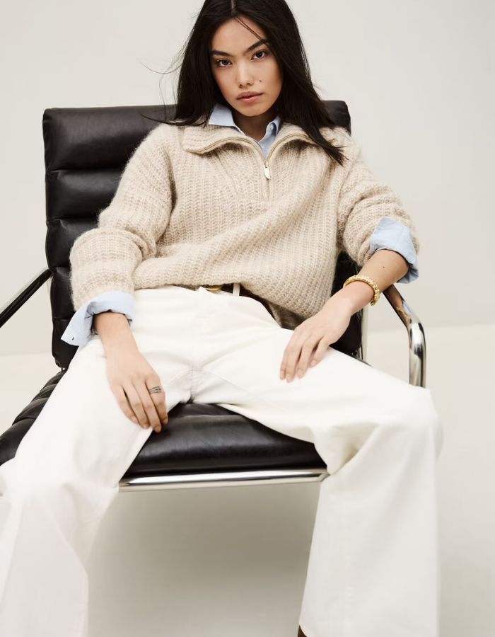 Femme assise portant un jean flare Badou écru taille basse en coton biologique avec empiècements.