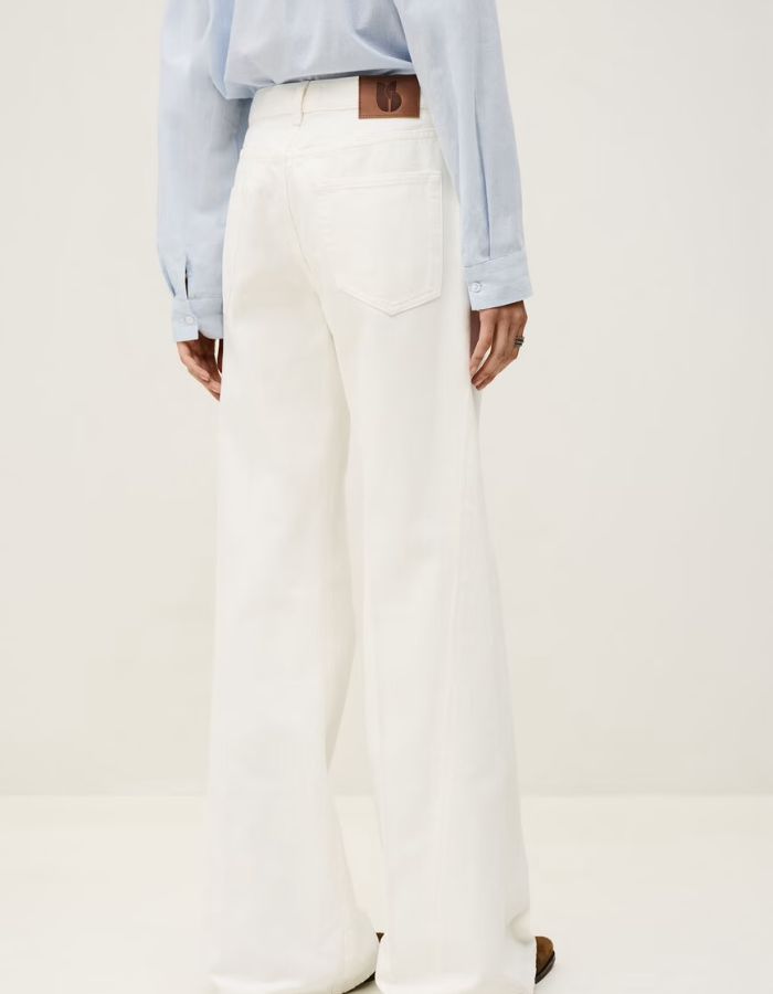 Jean flare Badou écru en coton biologique, taille basse, coupe large avec empiècement latéral et étiquette en cuir.