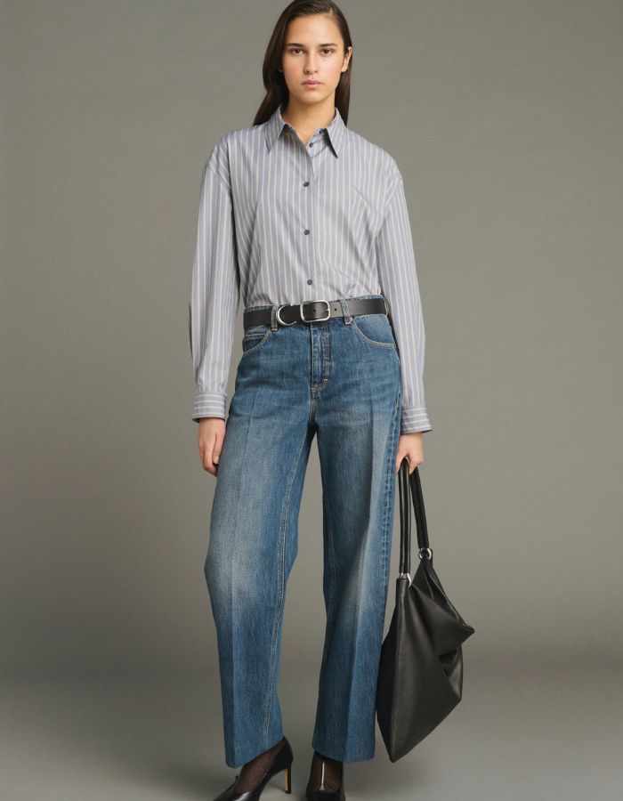 Silhouette avec le Jean droit pour femme en denim bleu délavé avec plis marqués devant et dos, modèle Jerry de la marque SOEUR. Présente une coupe droite 5 poches, une fermeture boutonnée zippée et un patch en cuir au dos.