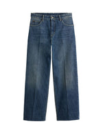 Jean droit pour femme en denim bleu délavé avec plis marqués devant et dos, modèle Jerry de la marque SOEUR. Présente une coupe droite 5 poches, une fermeture boutonnée zippée et un patch en cuir au dos.