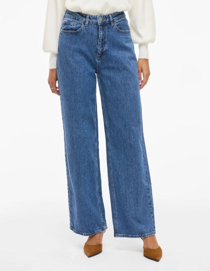 Silhouette de face avec le Jean large pour femme de couleur bleu moyen Medium Blue Denim, modèle Reya de la marque Vila. Présente une taille haute ajustée et des jambes amples fluides (coupe Frida), avec une fermeture par zip.