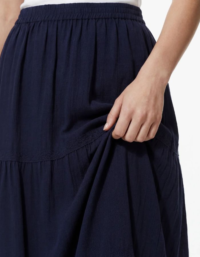 Détail de la Jupe longue taille haute Tohime par Pieces de couleur bleu marine (Maritime Blue). Coupe fluide longueur cheville en pur coton avec de délicates bandes de dentelle horizontales.