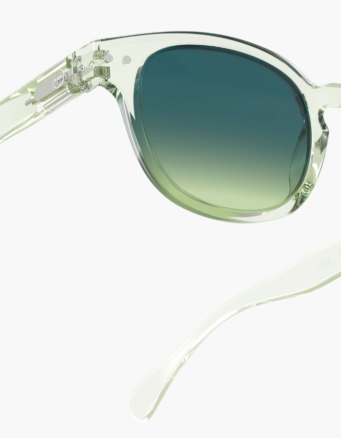 Côté des Lunettes de soleil unisexes IZIPIZI modèle #C de forme carrée vintage épaisse. La monture brillante est d'un coloris vert doux et légèrement translucide nommé Green Fields, associée à des verres solaires polarisés protecteurs