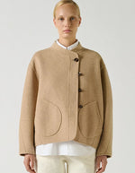 Devant du Manteau court pour femme en laine double face beige chiné, modèle Windsor de la marque SOEUR. Présente une coupe ample au volume rond, un col asymétrique, une patte de boutonnage semi-cachée et deux grandes poches plaquées sur le devant.