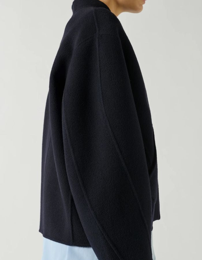 Manche du Manteau court pour femme en laine double face bleu marine profond Deep Navy, modèle Windsor de la marque SOEUR. Présente une coupe ample au volume rond, un col asymétrique, une patte de boutonnage semi-cachée et deux grandes poches plaquées sur le devant.