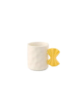 Mug en céramique blanc texturé avec anse jaune en forme de nœud papillon, design Fluid Market.