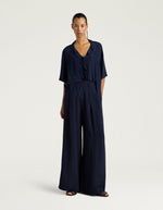 Silhouette avec le Pantalon large fluide style palace Aspen de la marque Momoni, coloris bleu uni. Coupe ample en crêpe d'acétate de soie avec plis élégants sur le devant, maxi passants à la taille et poches latérales.