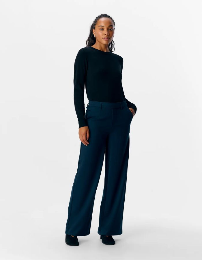 Silhouette avec le Pantalon large pour femme de couleur bleu marine foncé Sky Captain, modèle Lisa Wide Pant de la marque Object. Présente une coupe droite très ample de style wide-leg, une taille mi-haute froncée par un élastique confortable et des poches discrètes insérées dans les coutures latérales.