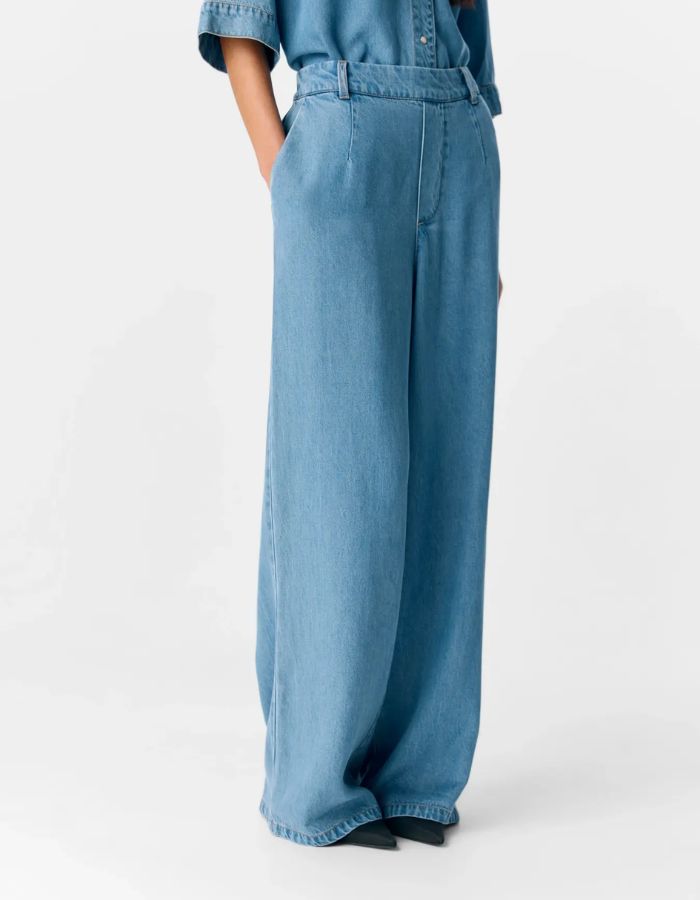 vue de côté du Pantalon large pour femme Lisa Wide de la marque OBJECT, coloris bleu denim clair. Coupe fluide à jambes larges, taille mi-haute avec passants de ceinture et poches latérales. Matière écologique en 100% Lyocell TENCEL