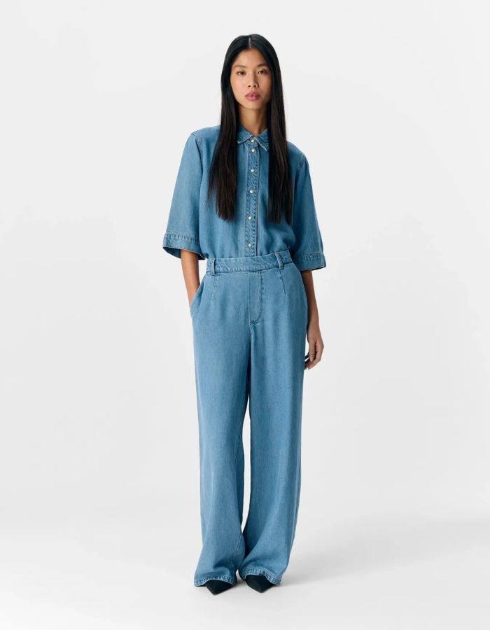 Silhouette avec le Pantalon large pour femme Lisa Wide de la marque OBJECT, coloris bleu denim clair. Coupe fluide à jambes larges, taille mi-haute avec passants de ceinture et poches latérales. Matière écologique en 100% Lyocell TENCEL