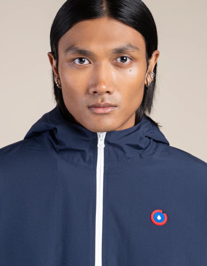 Col de la Parka imperméable mixte bleu indigo pour homme et femme, modèle Pompidou de la marque Flotte. Présente une coupe ajustée avec cordon de serrage à la taille, fermetures zippées étanches et doublure en polaire chaude.